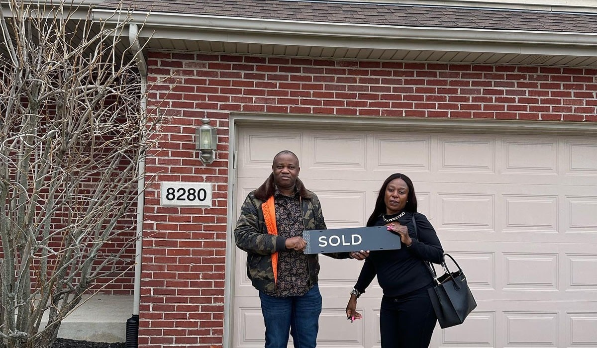two home buyers in front of the house they purchased, choose a recommended realtor